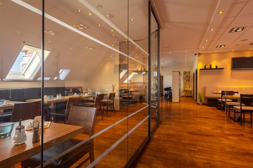 Hochwertige Innenaufnahme eines modern gestalteten Restaurant-Gastraums mit Holzboden und Glas-Trennwänden – Interior-Fotografie der Werbeagentur FourMedia.