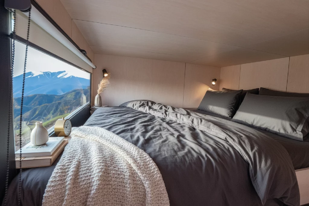 Ästhetische Innenaufnahme eines modernen, minimalistischen Schlafbereichs mit Panorama-Bergblick – High-End Werbefotografie der Agentur FourMedia.